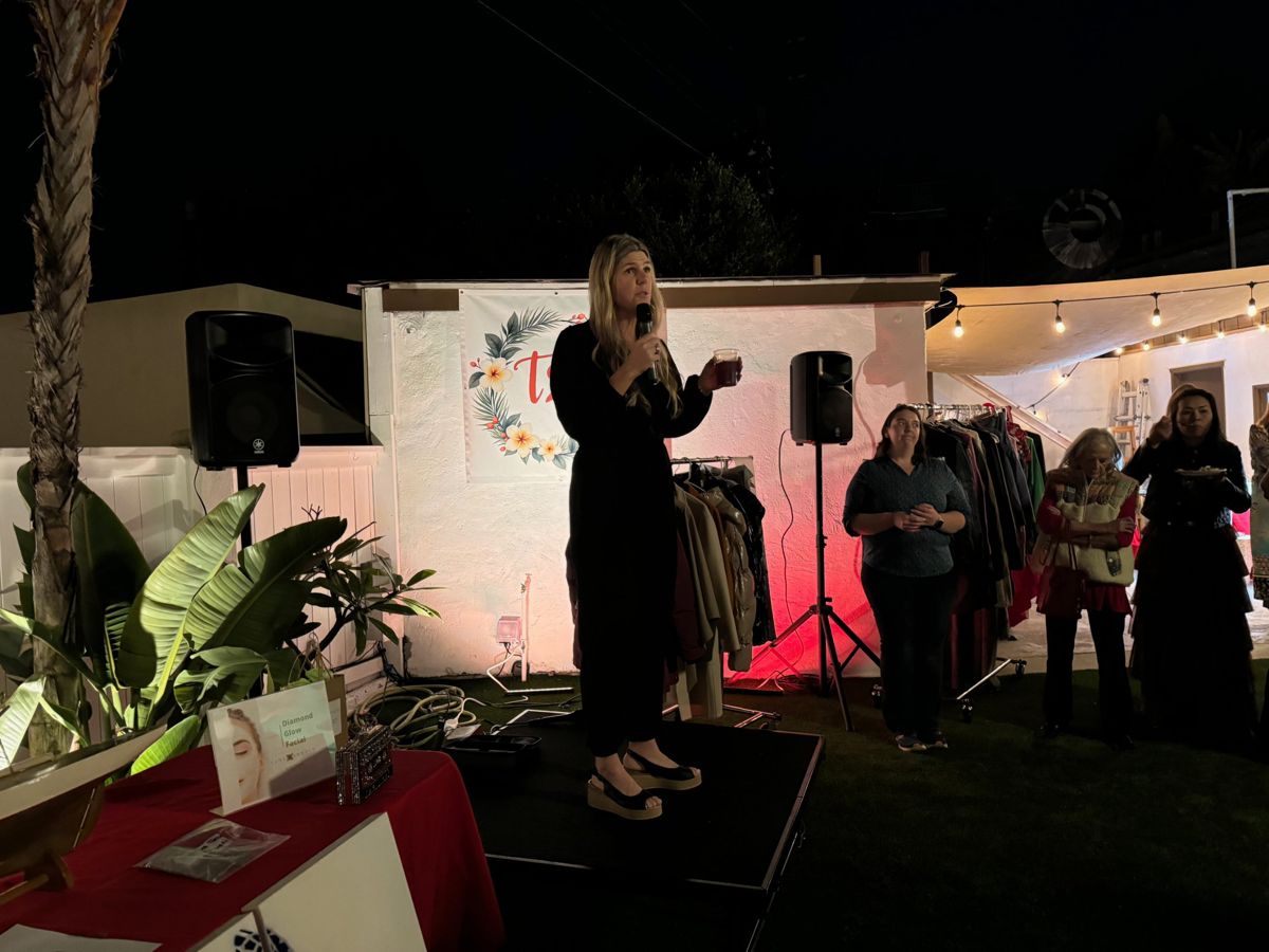 The live auction: a host on stage with a microphone beside racks of clothing