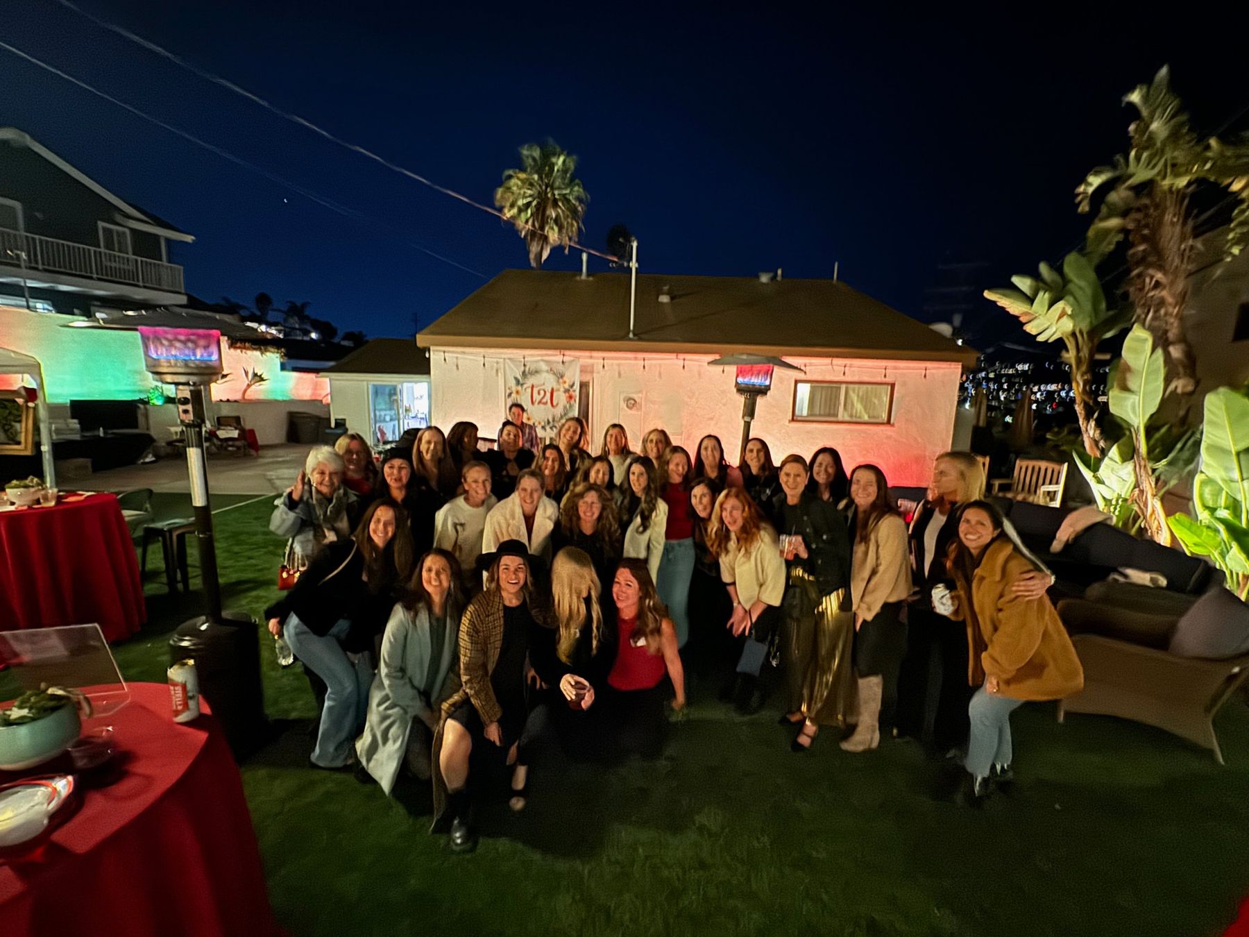 Dozens of women gathered for a group photo on the lawn at a past Trash 2 Treasure party