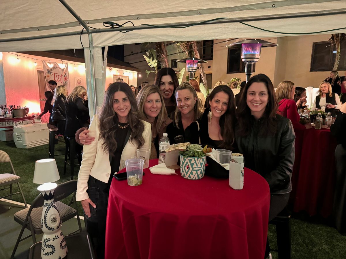 Five friends at a cocktail table with a red tablecloth